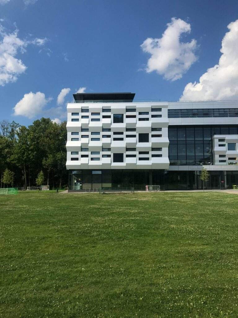 a large white building sitting on top of a lush green field